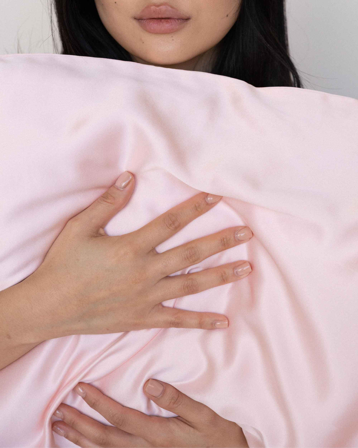 Hands resting on The Restore Case silk pillowcase