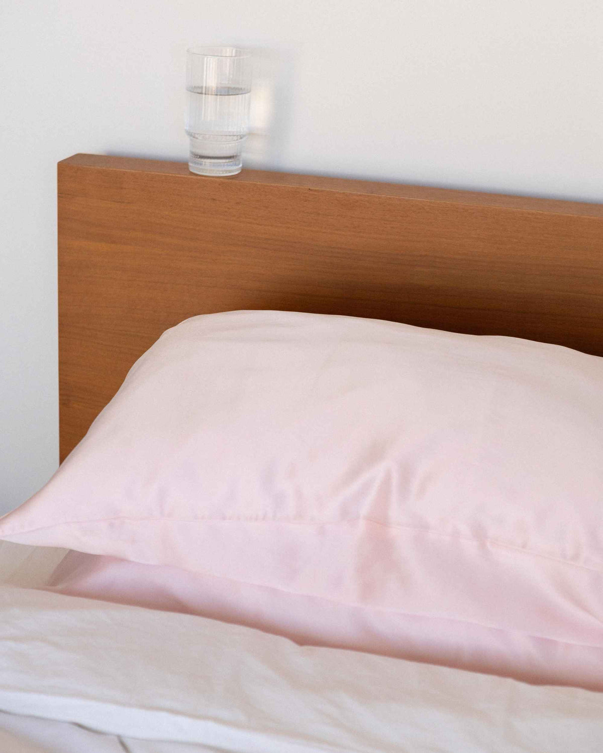 The Restore Case on a made bed with a timber headboard
