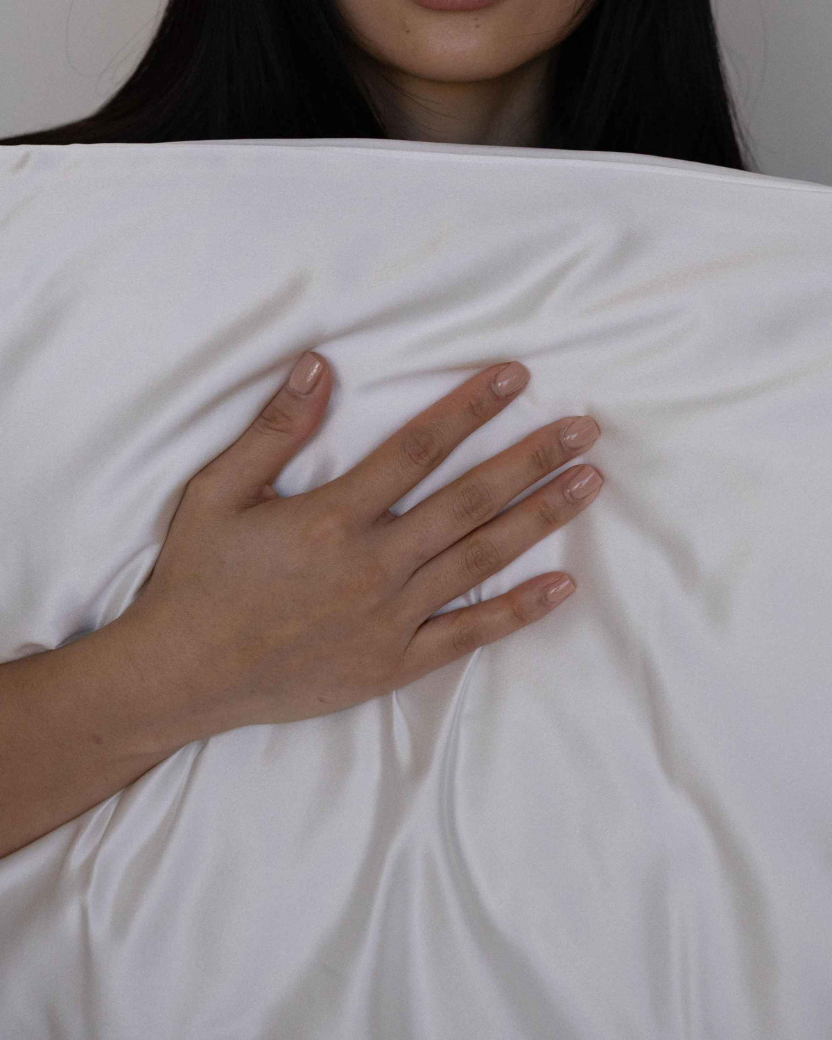 A hand resting on The Restore Case silk pillowcase