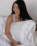 Cloud | Sitting up in bed laughing, hugging the cased pillow