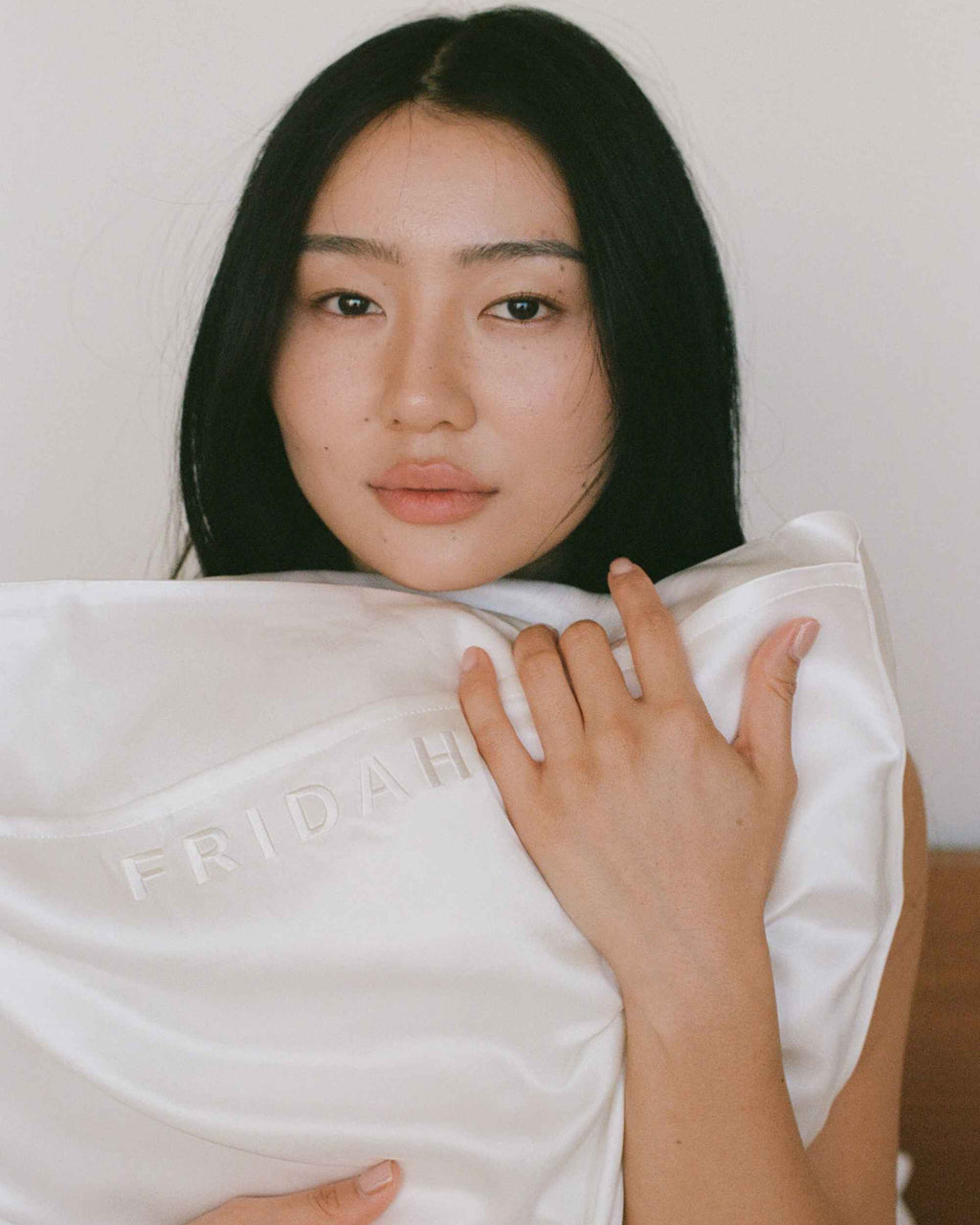 Holding the cased pillow to the face, embossed Fridah logo visible
