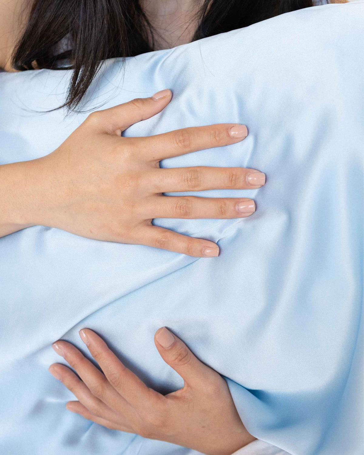 Hands resting on The Restore Case silk pillowcase