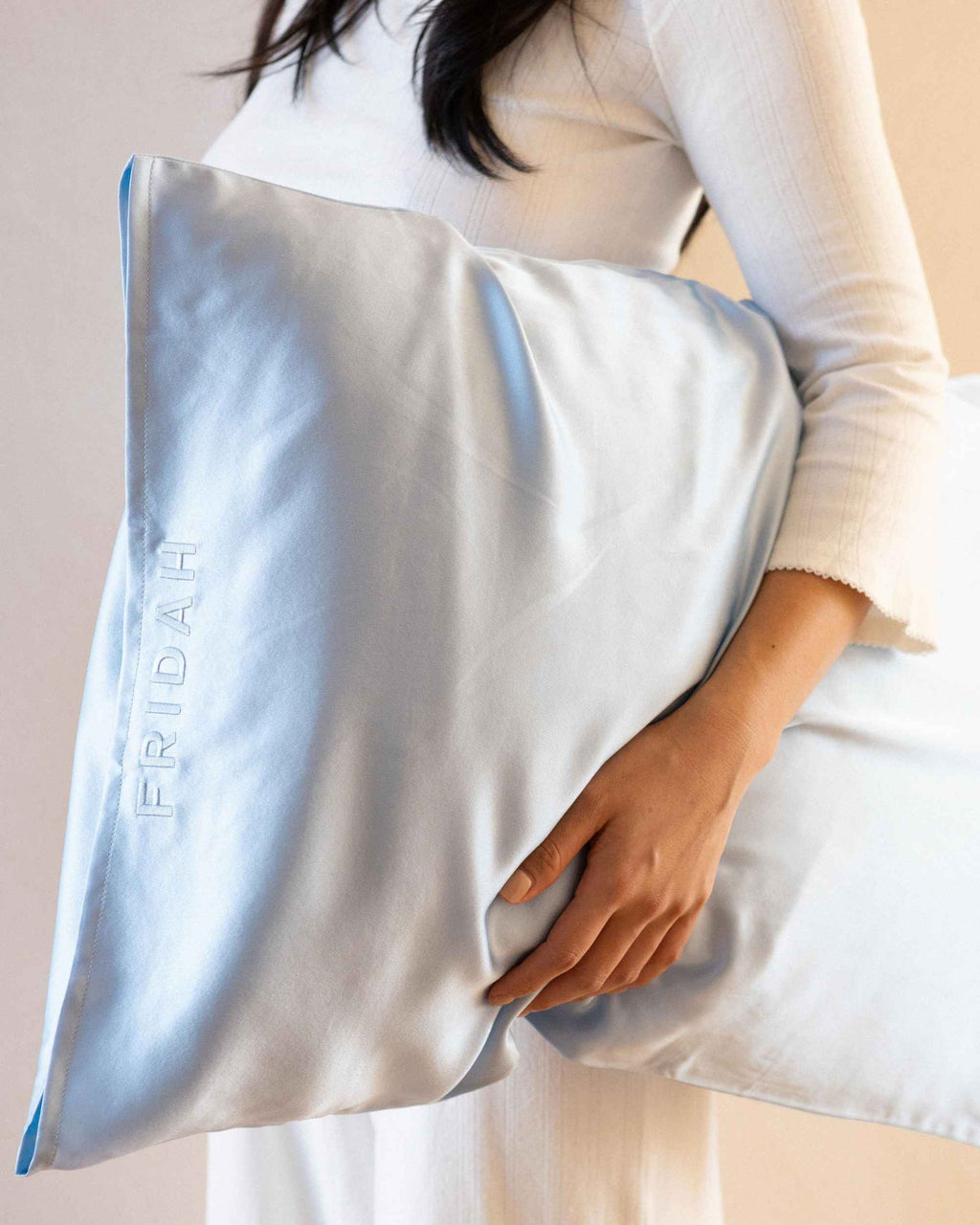 Holding the cased pillow, embossed Fridah logo visible